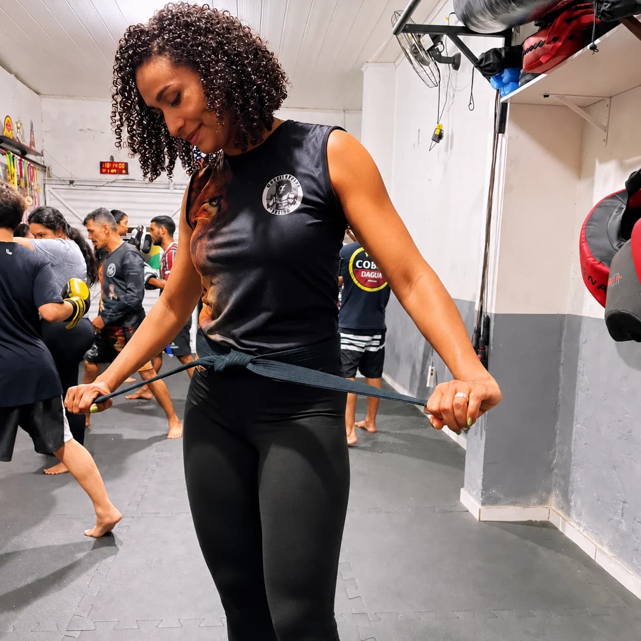 Professora Ellen Araújo ajustando a faixa preta durante treino na academia.